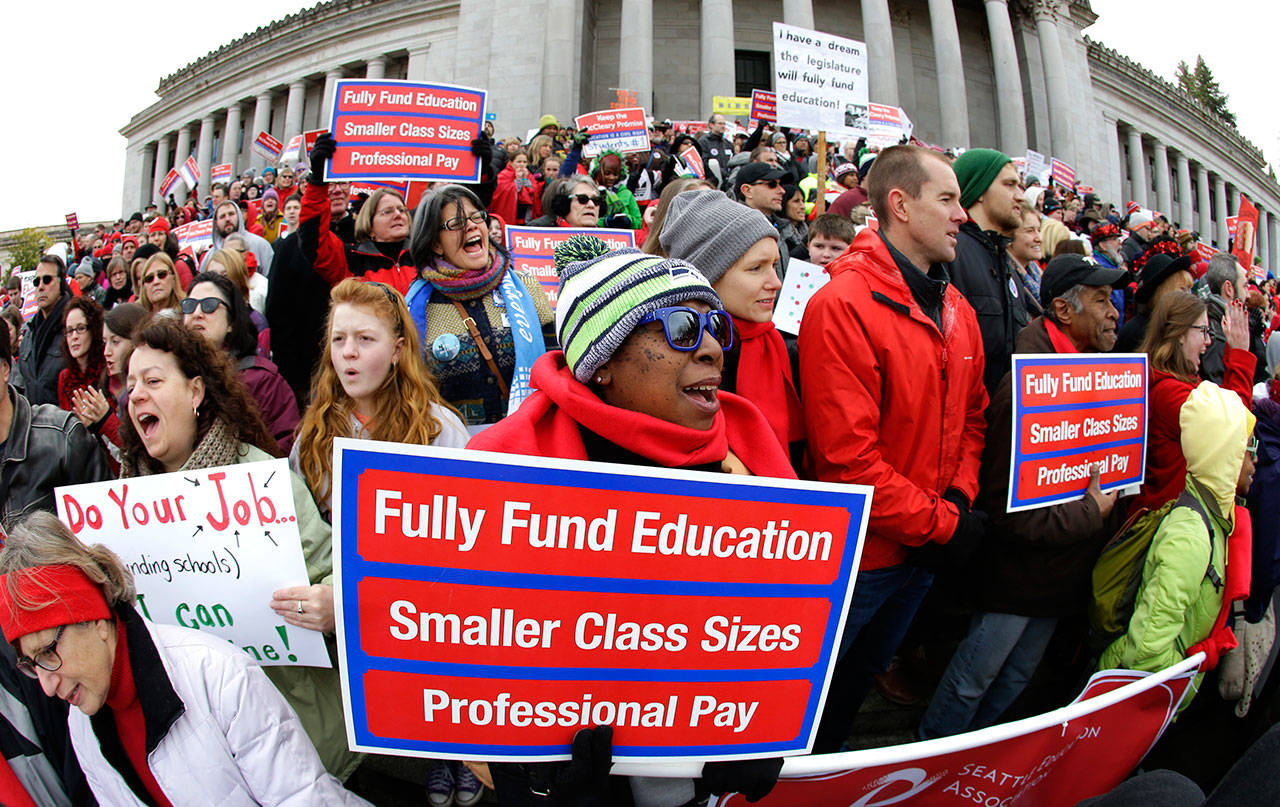 Oveta Hunter (center) an elementary school teacher from Seattle, cheers and holds a sign during a Jan. 16 rally in support of education funding at the Capitol in Olympia. The Washington State Supreme Court ruled last week that while lawmakers have made progress, they are not on track to meet a court-imposed deadline to fully fund basic education, and will remain in contempt of court. (Ted S. Warren/Associated Press file photo)