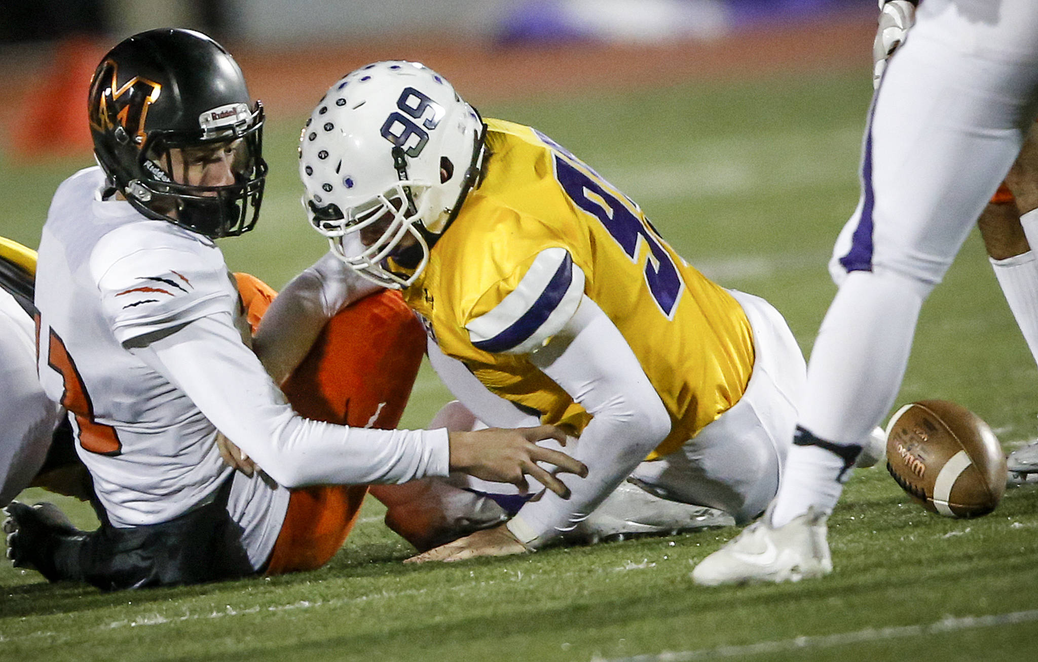 Monroe quarterback Jaedyn Prewitt (left) fumbles the ball as he’s hit by Sumner’s Dane Elwell (center) during a Class 4A state football quarterfinal game on Nov. 18, 2017, at Sunset Chev Stadium in Sumner. (Ian Terry / The Herald)