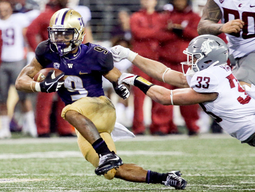 Washington Huskies running back Myles Gaskin rushes for yards with Washington State Cougars linebacker Dylan Hanser attempting a tackle Saturday night during the 110th Apple Cup at Husky Stadium in Seattle November 25, 2017. Washington won 41-14. (Kevin Clark / The Herald)
