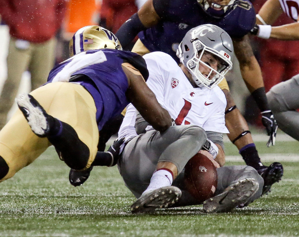 Washington Huskies linebacker Keishawn Bierria tackles Washington State Cougars quarterback Luke Falk and forces a fumble Saturday night during the 110th Apple Cup at Husky Stadium in Seattle November 25, 2017. Washington won 41-14. (Kevin Clark / The Herald)
