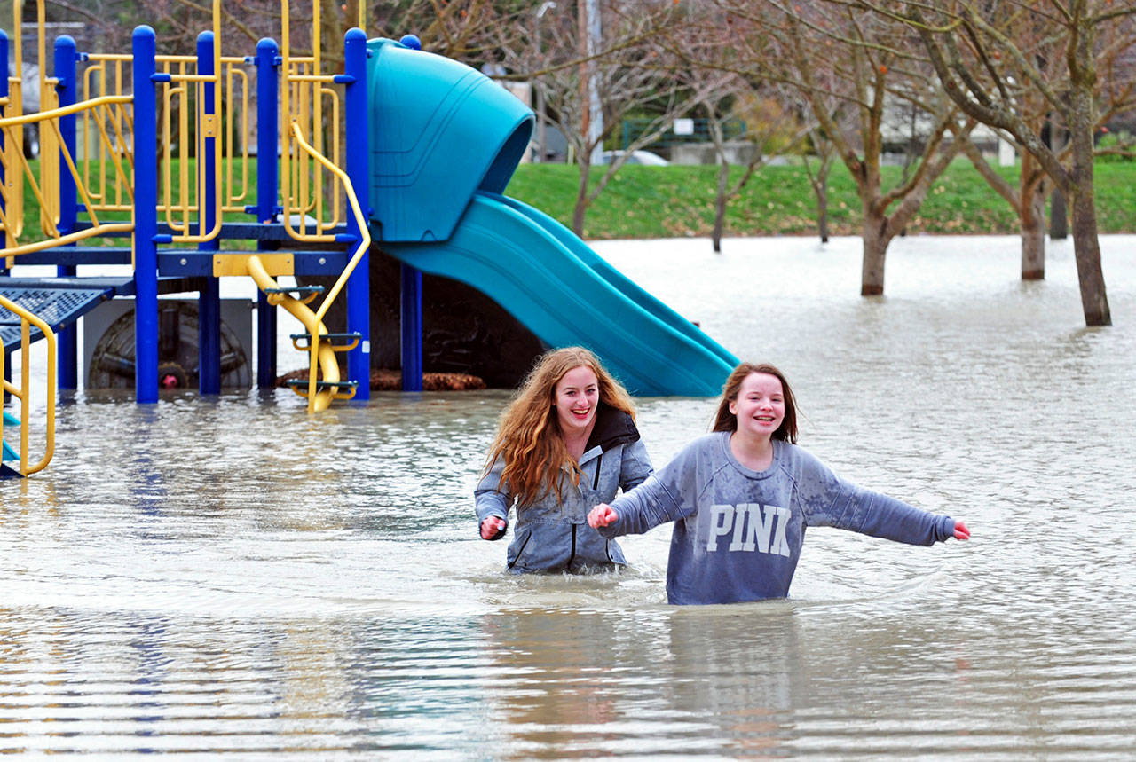 Cousins Keara (right) and Kennedy Fellers wade through flood waters on the playground at Edgewater Park Friday in Mount Vernon on Friday. Officials say that flooding was worse than expected on the Skagit River north of Seattle. (Charles Biles/Skagit Valley Herald via AP)