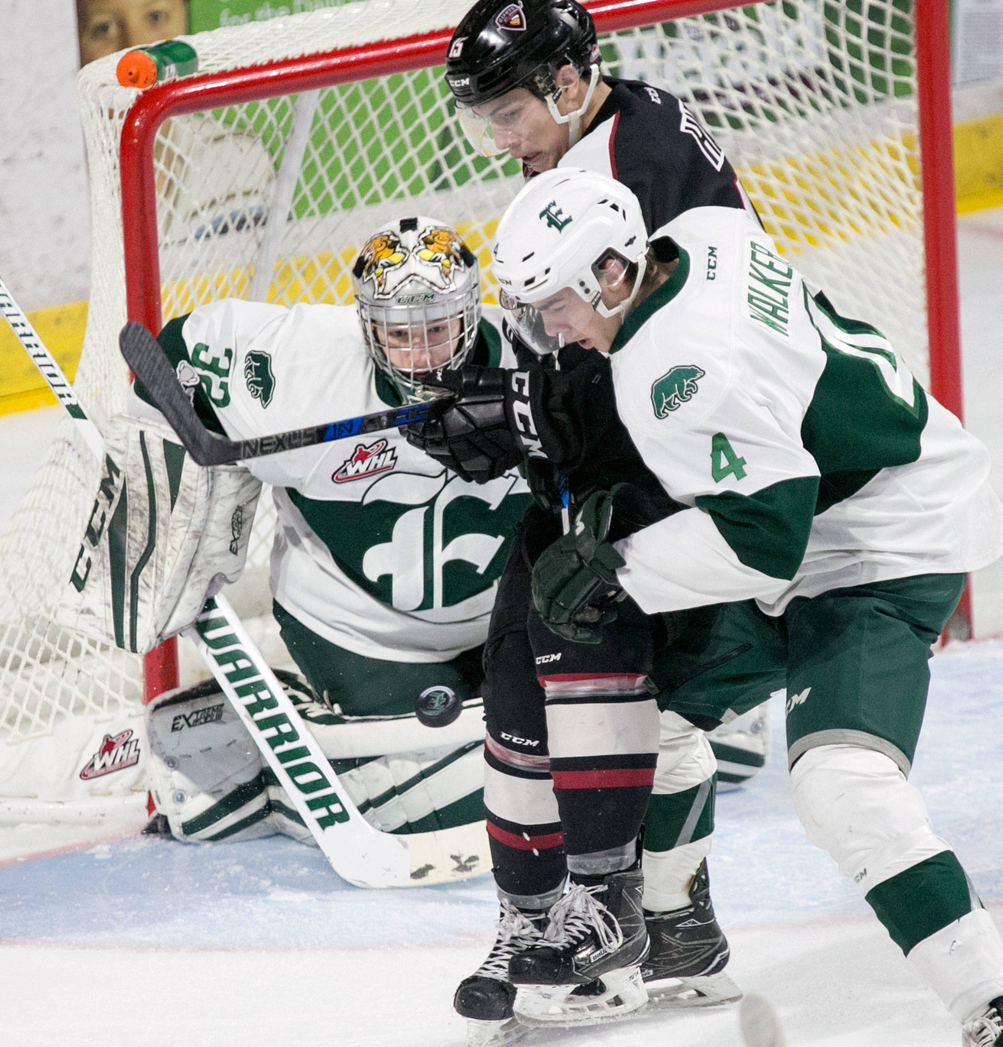 The Silvertips’ Dustin Wolf (left) defends the goal as teammate Ian Walker (4) battles Vancouver’s Owen Hardy for the puck in the first period of a game Dec. 29, 2017, at Angel of the Winds Arena in Everett. (Kevin Clark / The Herald)