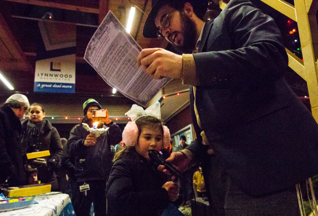 Rabbi Berel Paltiel holds the microphone so his 5-year-old daughter, Chaya Paltiel, can sing Chanukah songs at a celebration for the Festival of Lights during the fifth annual public Menorah Lighting Ceremony at Lynwood City Hall on Dec. 26 of last year. Nearly 50 gathered to sing, eat and celebrate the third night of Chanukah. (Daniella Beccaria / Herald file)
