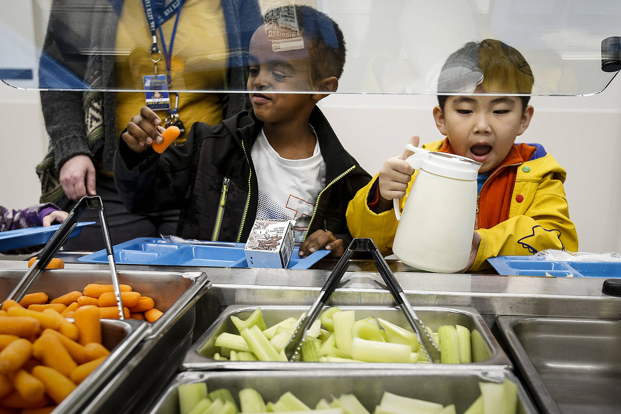 Kindergartner Maereg Andualem (left) checks out a carrot while fellow classmate Alex Shim helps himself to some dressing during lunchtime at Lynndale Elementary School in Lynnwood on Thursday, Nov. 30. (Ian Terry / The Herald)