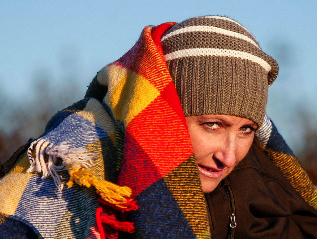 In a bone-chilling wind on the Mukilteo beach Tuesday, Heather Lopez tries to stay warm beneath a blanket and her fiance’s jacket. Heather is battling cancer and it isn’t good news. The doctor’s advice is to do what she wants, do what matters—and do it now. (Dan Bates / The Herald)
