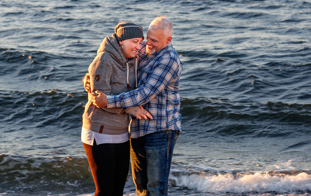 Heather Lopez’s fiance Jimmy Absher steadies her while photographer Tessa Burrus take photos of the couple along the shoreline. Temperatures Tuesday were a chilling problem for most people, but especially for Heather. (Dan Bates / The Herald)
