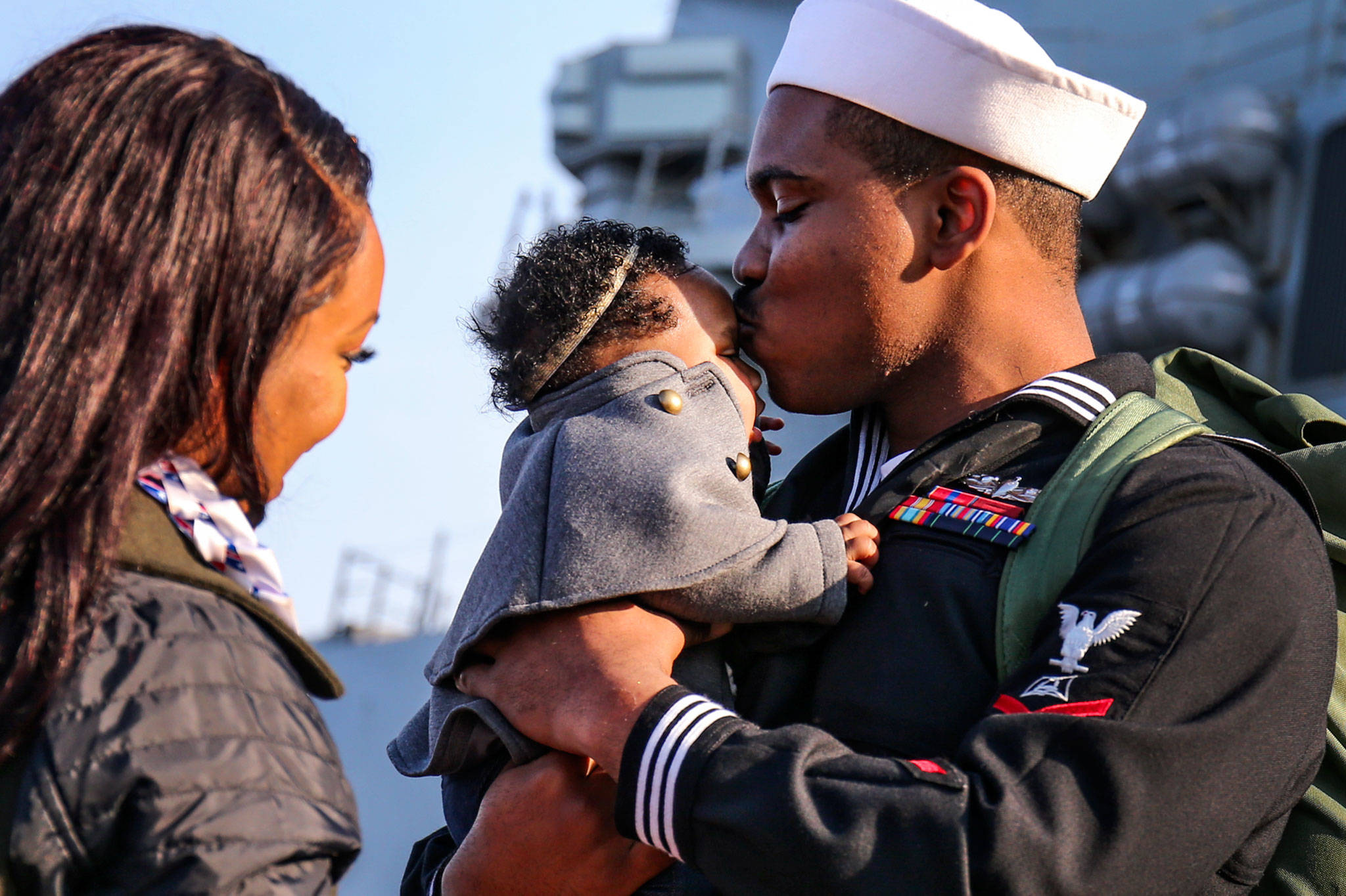 Christian Drew kisses his daughter, Jaelyn Drew, as Christina Drew (left) looks during the homecoming of the USS Kidd on Sunday morning at Naval Station Everett. (Kevin Clark / The Herald)
