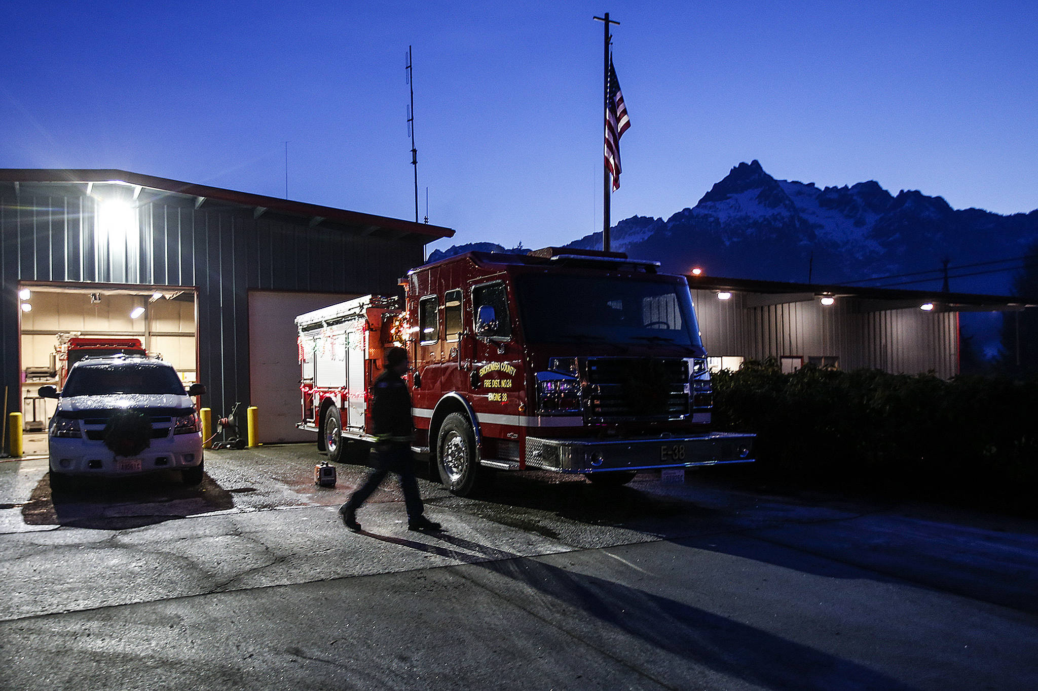 Darrington Fire Capt. Drew Bono walks in front of engine 38 as Whitehorse Mountain glows faintly in the evening light on Tuesday, Dec. 12. Darrington is one of Snohomish County’s few towns that rely on a true volunteer fire department. (Ian Terry / The Herald)