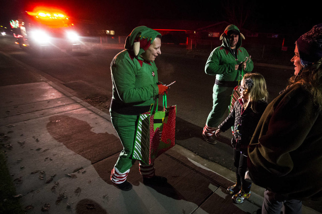 Dressed as elves, volunteer firefighters Angela Botamanenko (center) and Tim Ziesemer (right) hand out candy canes during a Christmas Parade on the streets of Darrington on Tuesday, Dec. 12. (Ian Terry / The Herald)
