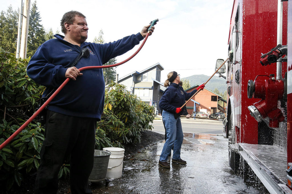 Darrington firefighter Larry Schoder (left) rinses off a fire engine on Tuesday, Dec. 12. Schoder and his wife, Kris, are both volunteers at the station. (Ian Terry / The Herald)
