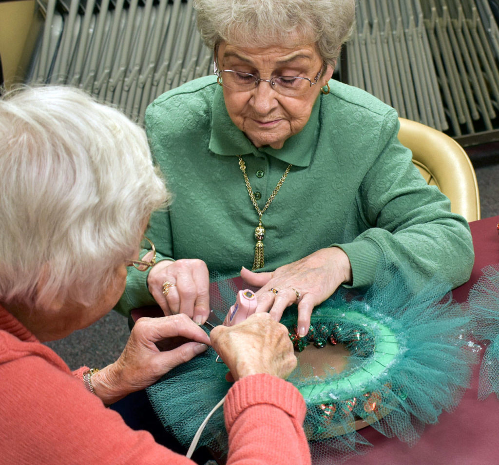 Aleph Swanson (left) and Pearl Hebert glue ruffled netting to a candy wreath. (Melissa Slager / The Daily Herald)
