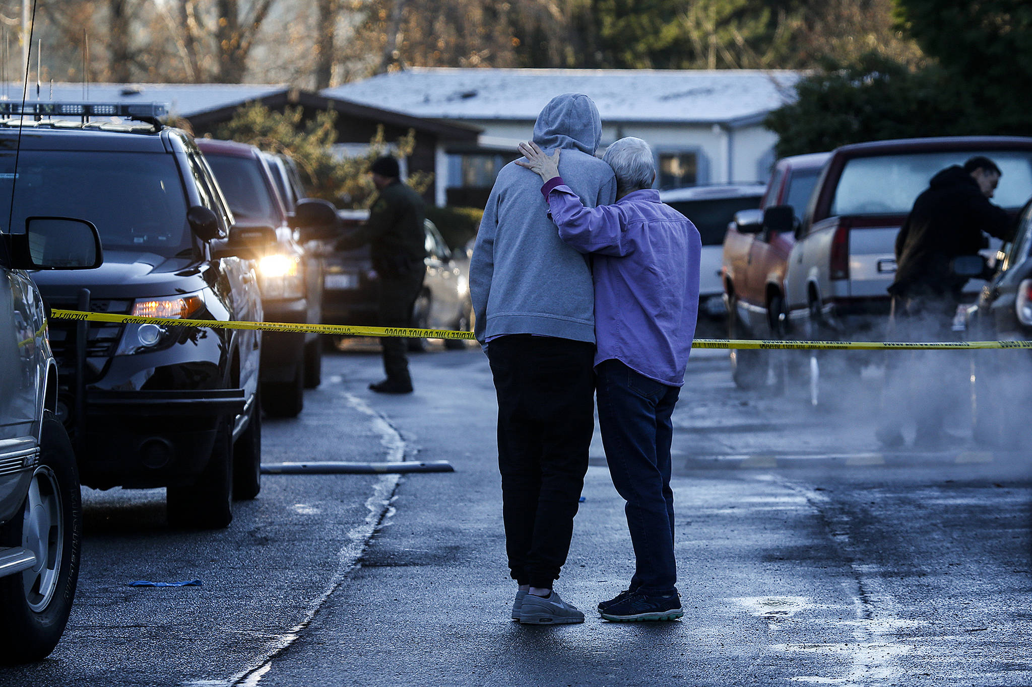 A man and woman embrace as they look towards a home where a 54-year old woman was shot and killed early Thursday morning in the Village Green Mobile Home Park near East Gibson Road in south Everett. (Ian Terry / The Herald)