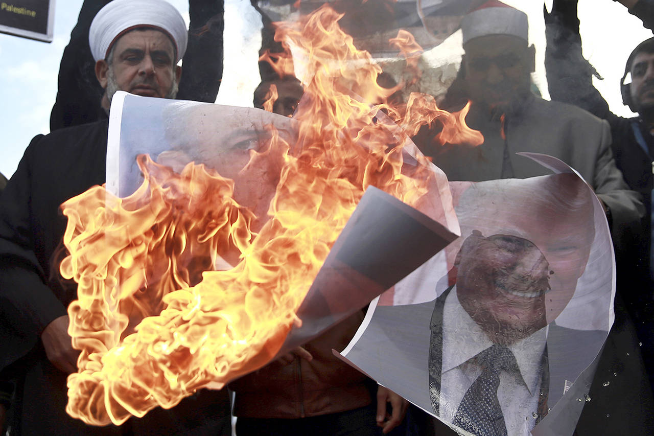 Palestinians burn posters of Israeli Prime Minister Benjamin Netanyahu and U.S. President Donald Trump, during a protest against the U.S. decision to recognize Jerusalem as Israel’s capital, in Gaza City on Thursday. (AP Photo/ Khalil Hamra)