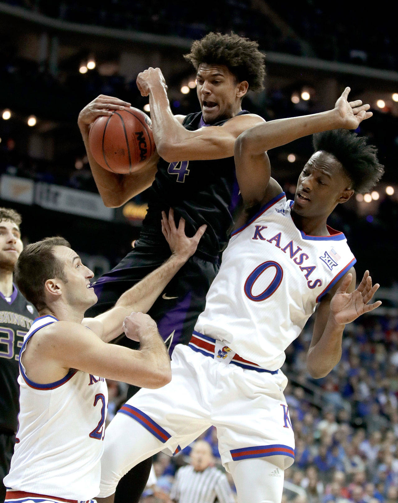 Washington’s Matisse Thybulle beats Kansas’ Clay Young (left) and Marcus Garrett to a rebound during the first half of Wednesday’s game in Kansas City, Mo. (AP Photo/Charlie Riedel)