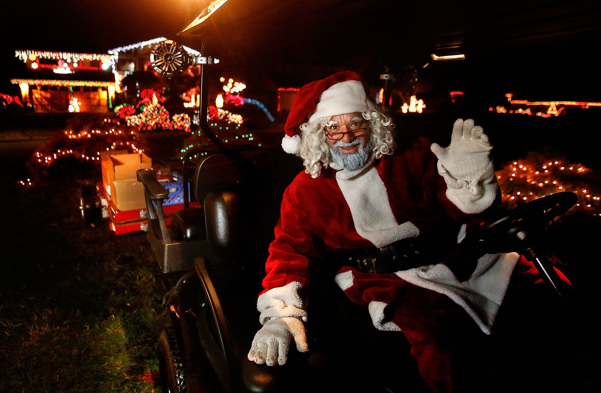 Community Transit bus driver Paolo Stracqualursi, who plays Santa every night until Christmas in Everett’s Fir Grove neighborhood, arrives on a golf cart-sleigh to pass out candy canes and collect canned food and cash donations for Volunteers of America. (Dan Bates / The Herald)