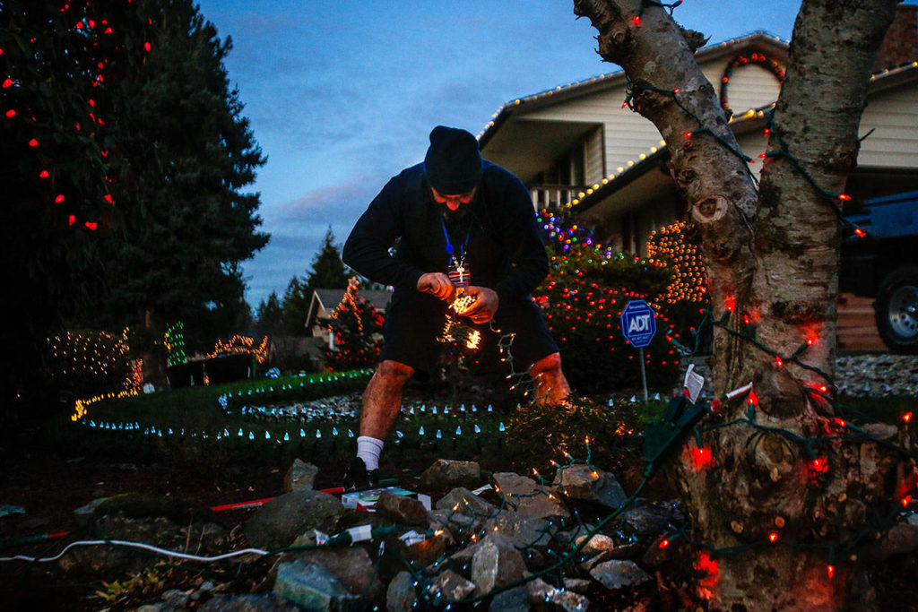 Before changing into his Santa suit, Community Transit bus driver Paolo Stracqualursi adds more lights to what he guesses to be about 5,000 lights on his own house and yard in Everett’s Fir Grove neighborhood. Stracqualursi plays Santa every night, collecting donations for Volunteers of America, till Christmas, arrives. (Dan Bates / The Herald)
