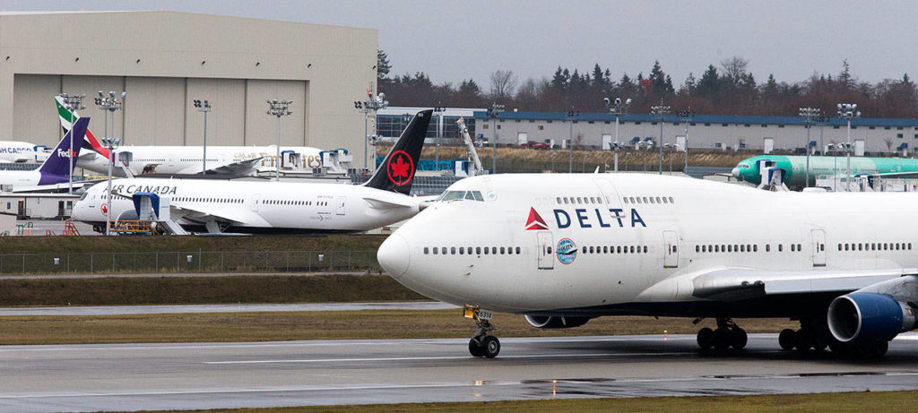 A Delta Air Lines 747-400 taxis past newer model Boeing planes after landing at Paine Field during a stop on the plane’s a farewell tour on Monday.. (Andy Bronson / The Herald) 

