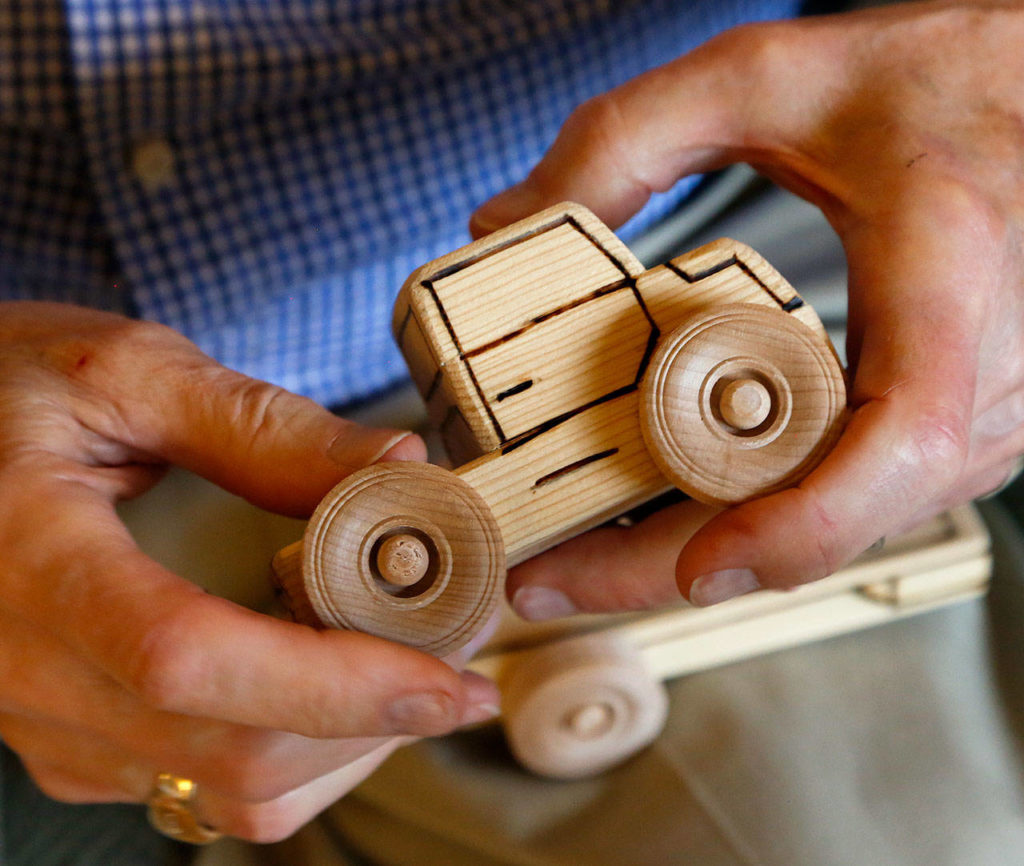 Leroy McVay, 85, of Everett, makes wooden toys to be donated to children. He uses a wood-burning pen for detail work on a variety of trucks, trains, tractors and more. (Dan Bates / The Herald)
