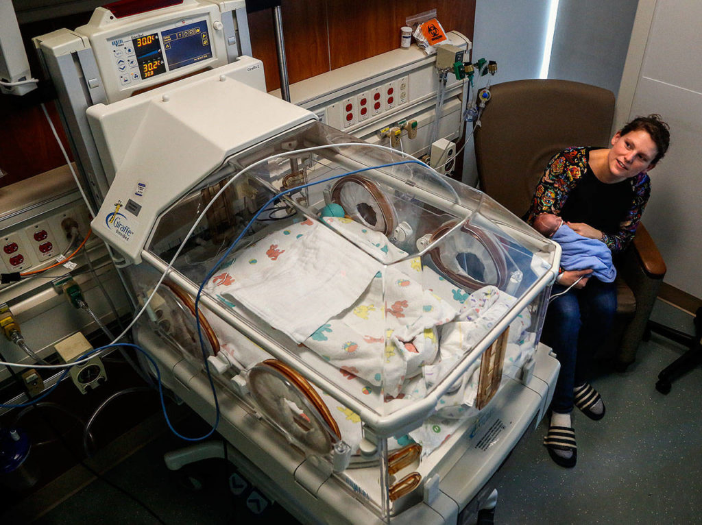 Holding her tiny son, Hugo, Elisabeth Strom peers over his enclosed medical isolette to see what’s up with his monitor, which beeps once in a while. (Dan Bates / The Herald)
