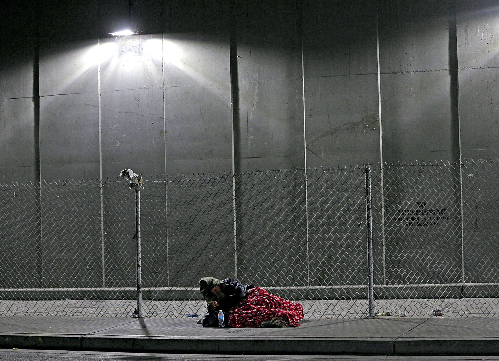 A homeless man rests on a sidewalk under the Smith Avenue Bridge in Everett, which is a constant gathering place for homeless people battling addiction and mental illness. The city has tried to identify and work with the top chronic and costliest users of emergency and other services, but despite the efforts of a specialized team of experts, many remain on the streets. (Ted S. Warren / Associated Press)