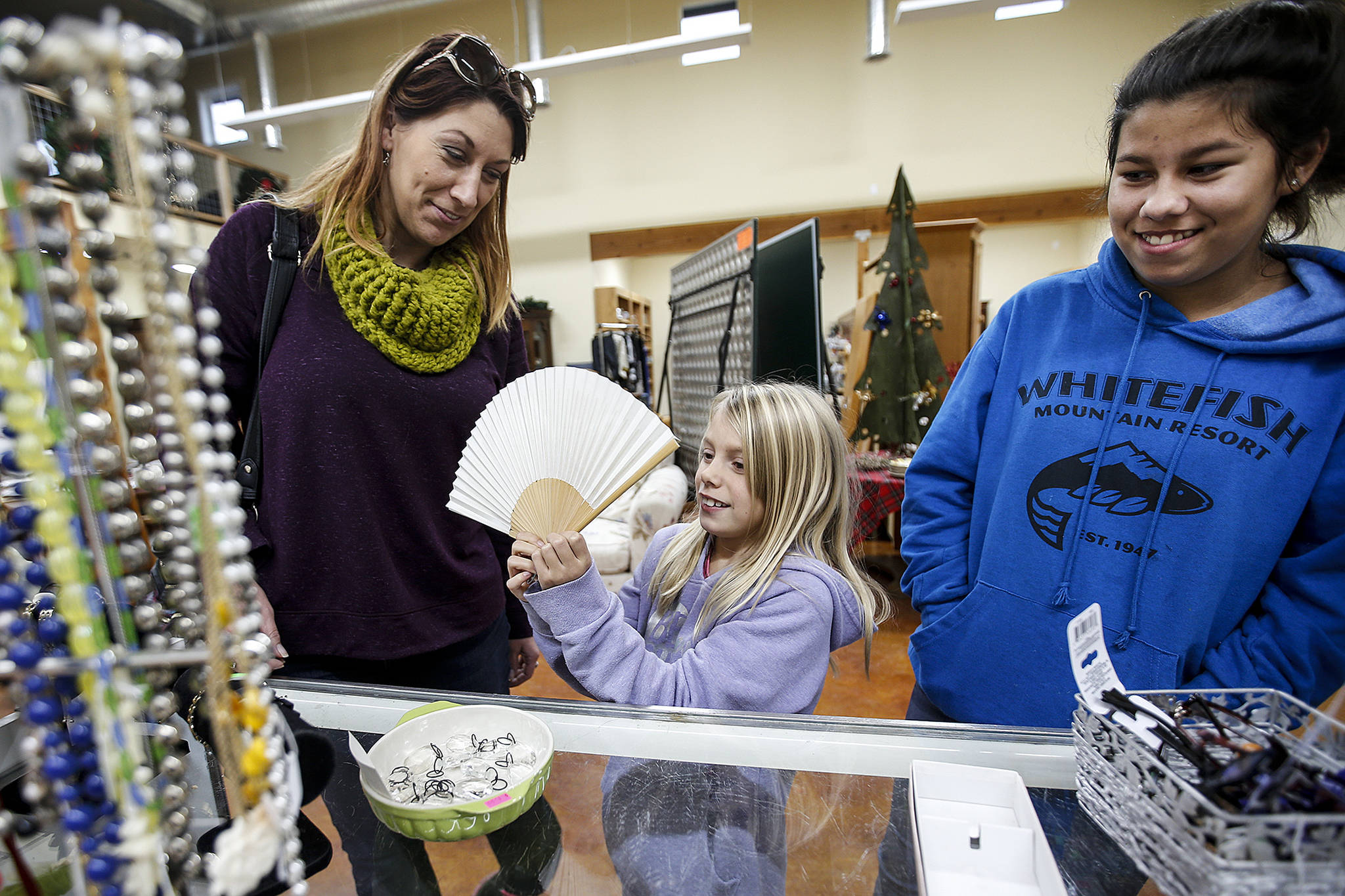 Charlie Fredricks-Fields, 6, checks out a painted fan with her mom, Rheann Fredricks, and sister Riley Nochlin, 12, (right) at Second Chance Thrift Shop on Camano Island on Thursday. The thrift store, located on Highway 532 near Stanwood, just finished a six-month, $613,000 project to add a second building. (Ian Terry / The Herald)