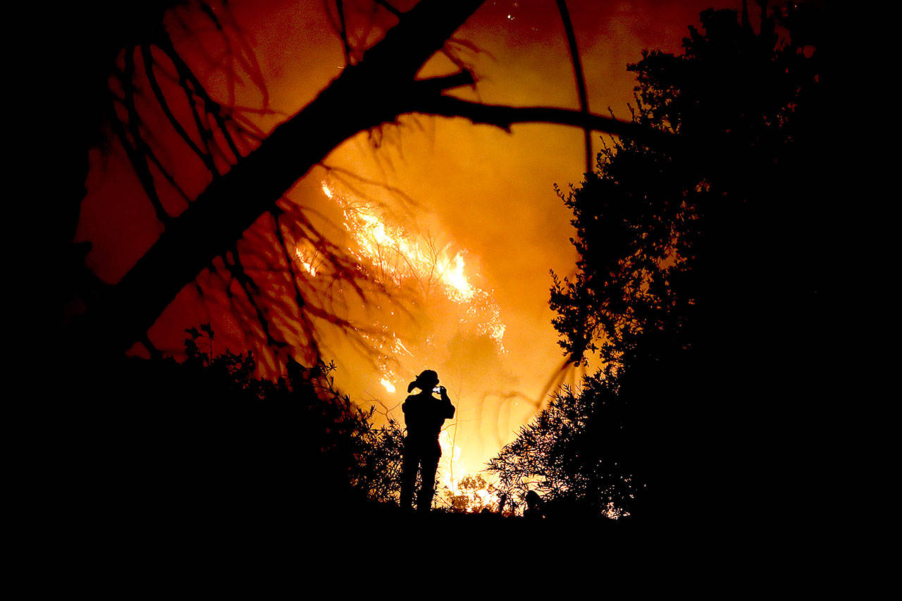 A firefighter takes a cellphone picture during a wildfire Saturday in Montecito, California. (AP Photo/Chris Carlson)