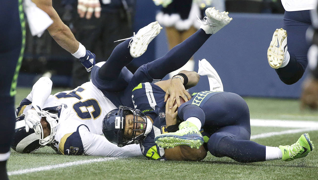 Seattle Seahawks quarterback Russell Wilson is sacked by Los Angeles Rams outside linebacker Robert Quinn in the second half of Sunday’s NFL game in Seattle. (AP Photo/Elaine Thompson)