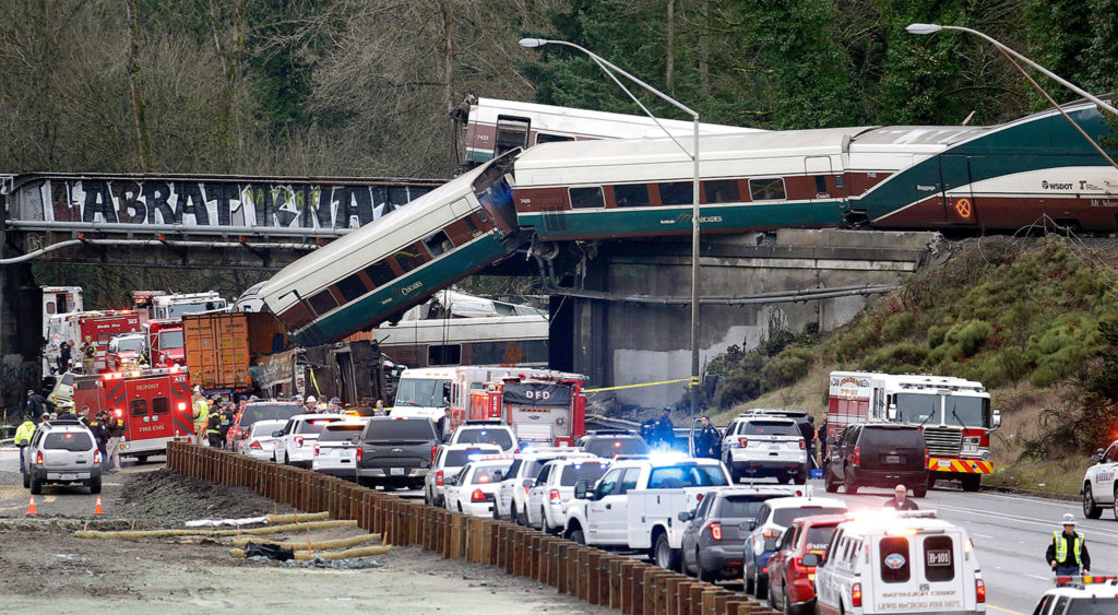 Some cars of an Amtrak train are spilled onto I-5 and some remain on the tracks above on Monday near DuPont. (AP Photo/Elaine Thompson) 
