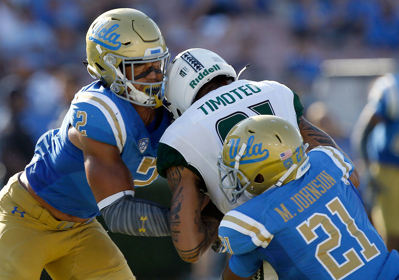 UCLA linebacker Josh Woods (left) makes helmet-to-helmet contact with Hawaii wide receiver Kalakaua Timoteo during a game in September. Woods was penalized for targeting on the play and ejected. (AP Photo/Alex Gallardo, File)