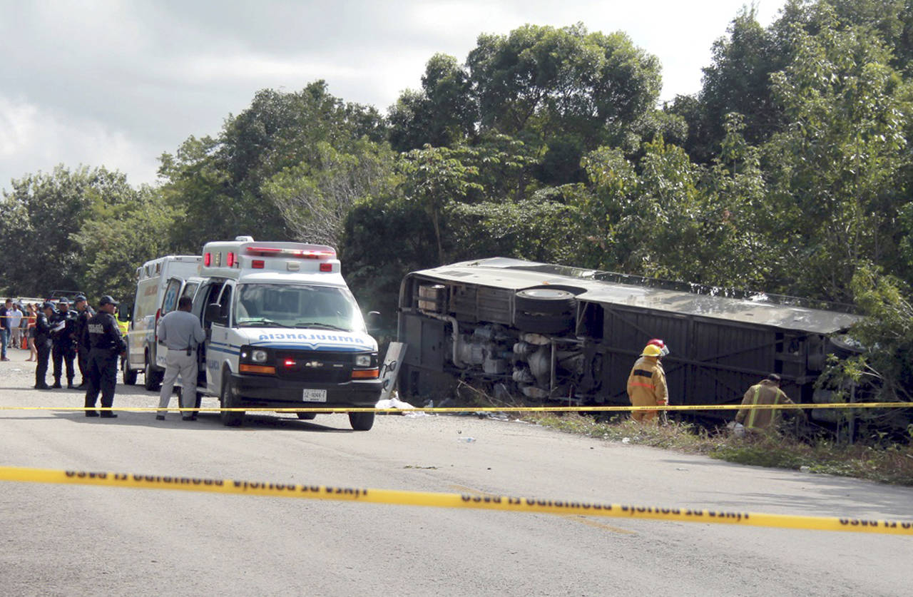 An ambulance sits parked next to an overturned bus in Mahahual, Quintana Roo state, Mexico, on Tuesday. (Novedades de Quintana Roo via AP)