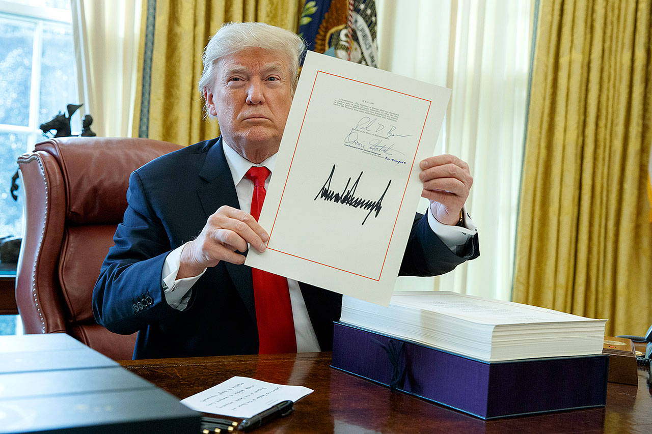 President Donald Trump shows off the tax bill after signing it in the Oval Office of the White House on Friday in Washington. (AP Photo/Evan Vucci)