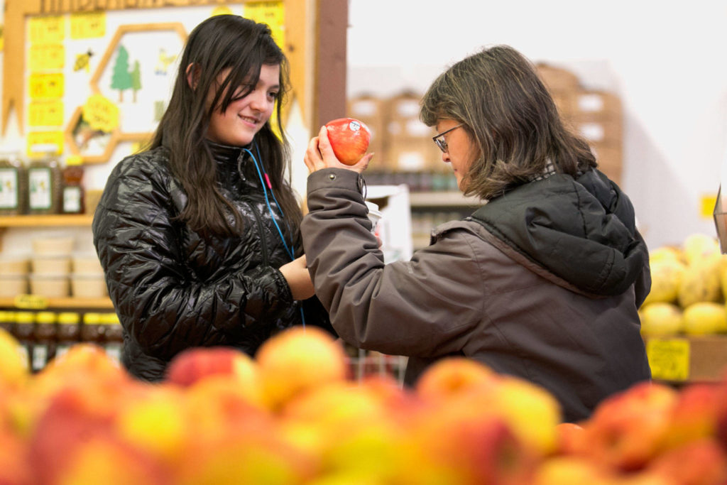 Olivia Nishimoto (left) and her mother, Ginger Nishimoto, browse apples Thursday night at Produce Place in Marysville. (Kevin Clark / The Daily Herald)
