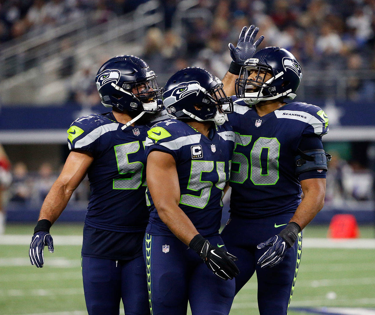 Seahawks outside linebacker Michael Wilhoite (57) and middle linebacker Bobby Wagner (54) congratulate outside linebacker K.J. Wright (50) after his interception against the Cowboys on Dec. 24, 2017, in Arlington, Texas. (AP Photo/Michael Ainsworth)