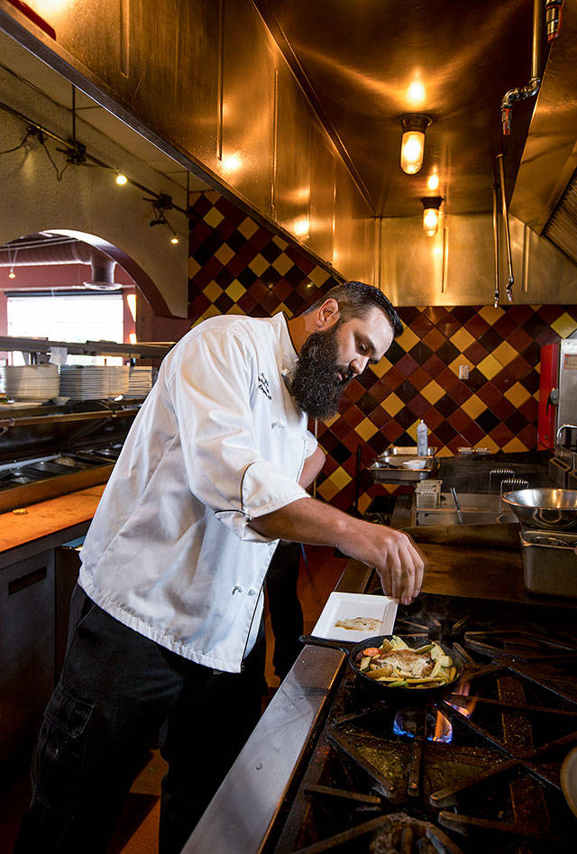 Lombardi’s Executive Chef Andy Hilliard sprinkles herbs on vegetables as he makes a 40 Clove Chicken entree. (Andy Bronson / The Herald)