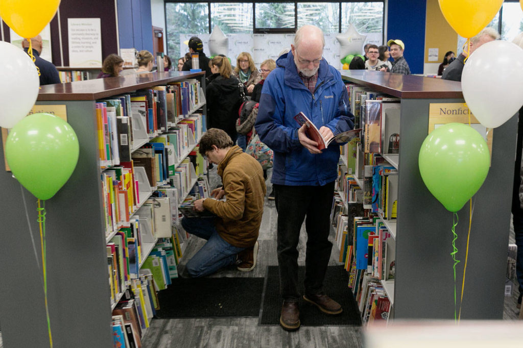 Crowler Cremson, left, and Ken Wild, right, browses the shelves during the grand opening of the new Lakewood/Smokey Point Library Saturday morning in Arlington on January 6, 2018. (Kevin Clark / The Daily Herald)
