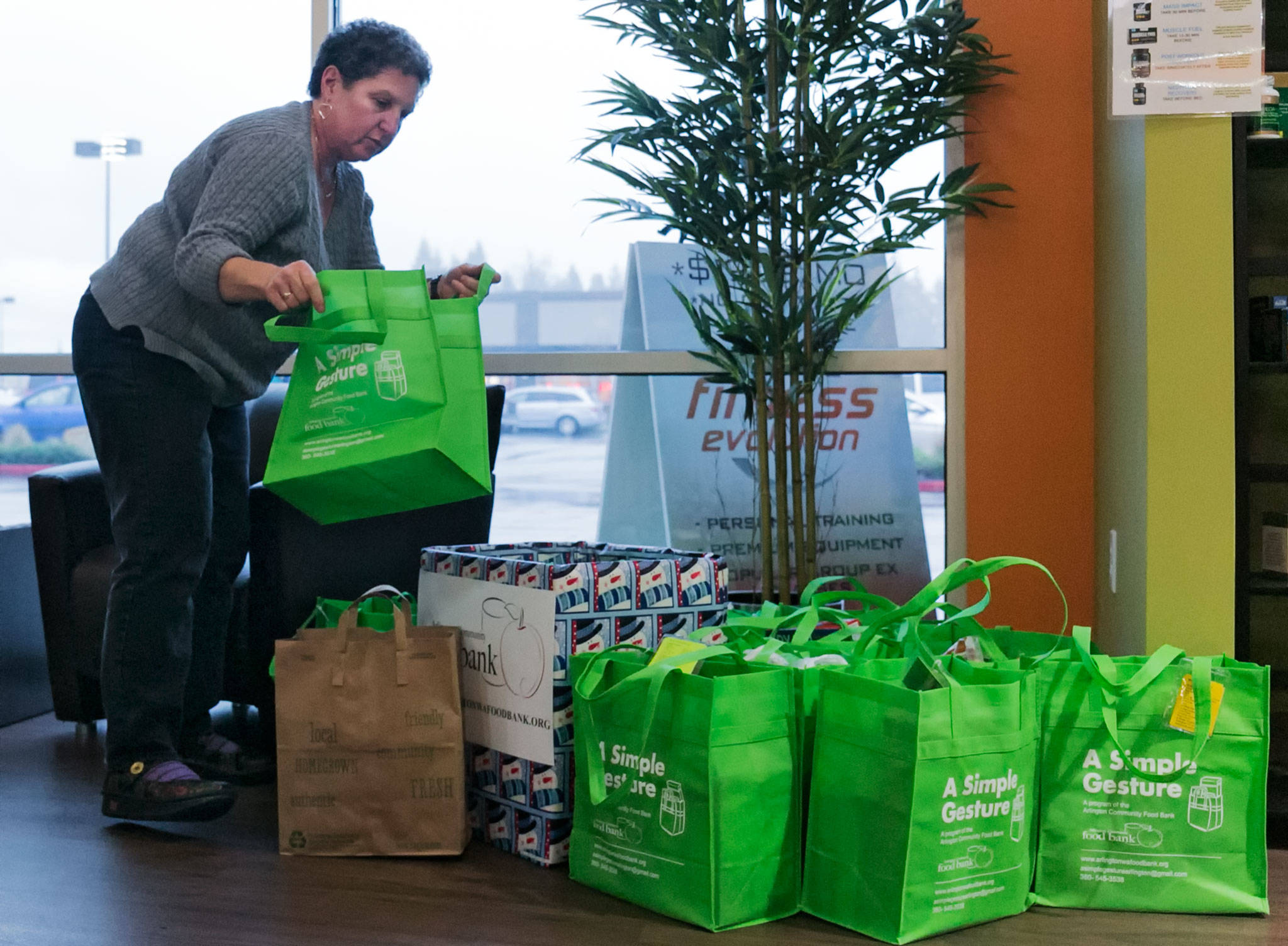 Faith Martian places newly donated food in bags at Fitness Evolution, the communal pick-up point, in Arlington on Jan. 12. (Kevin Clark / The Herald)