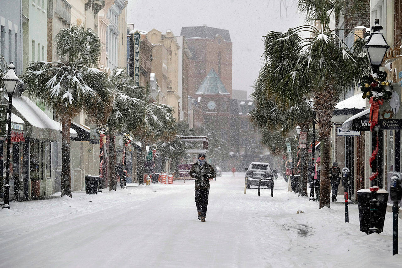 A person walks in the snow on King Street in Charleston, South Carolina, on Wednesday. A brutal winter storm smacked the coastal Southeast with a rare blast of snow and ice Wednesday, hitting parts of Florida, Georgia and South Carolina with their heaviest snowfall in nearly three decades. (Matthew Fortner / The Post And Courier)