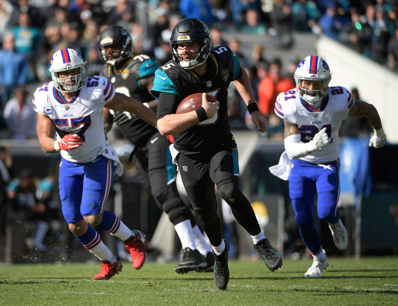 Jacksonville quarterback Blake Bortles (5) runs with the ball as Buffalo’s Lorenzo Alexander and Jordan Poyer give chase in the first half of Sunday’s playoff game. (AP Photo/Phelan M. Ebenhack)