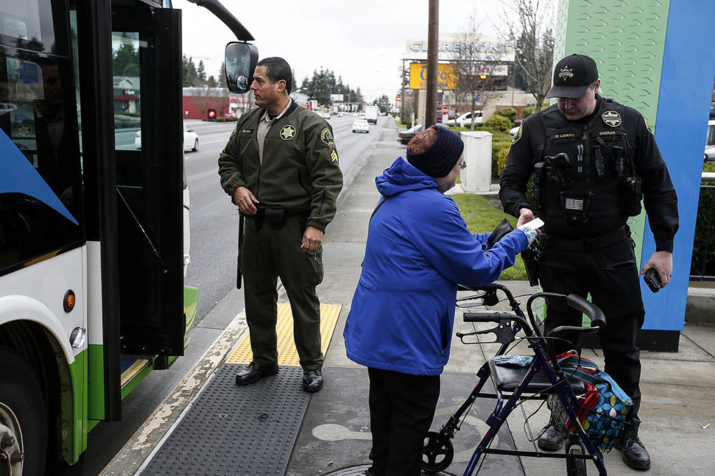 Snohomish County Sheriff’s deputy Brandon Liukko checks a bus passenger’s ticket as Sgt. Marty Zelaya waits for other passengers to unload on Evergreen Way in Everett on Wednesday. (Ian Terry / The Herald)
