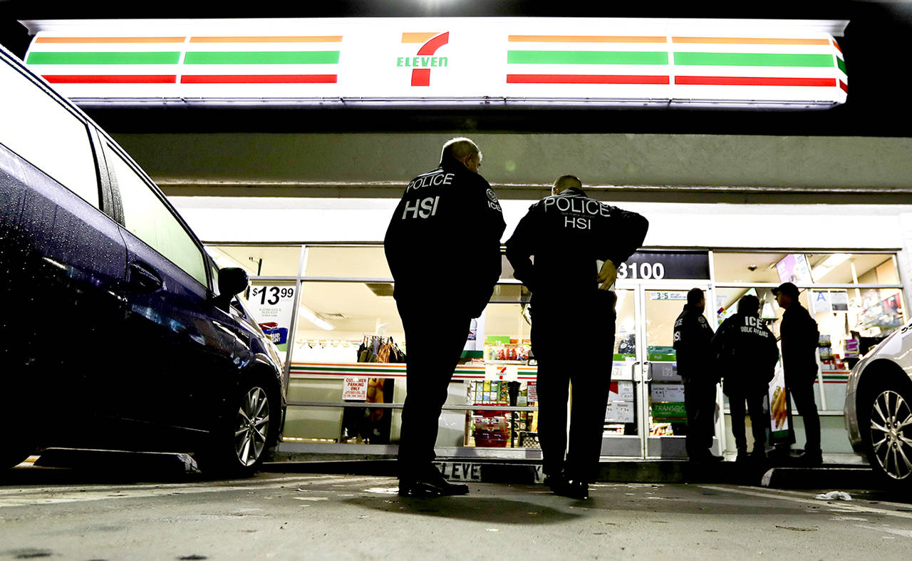 U.S. Immigration and Customs Enforcement agents serve an employment audit notice at a 7-Eleven convenience store Wednesday in Los Angeles. (AP Photo/Chris Carlson)