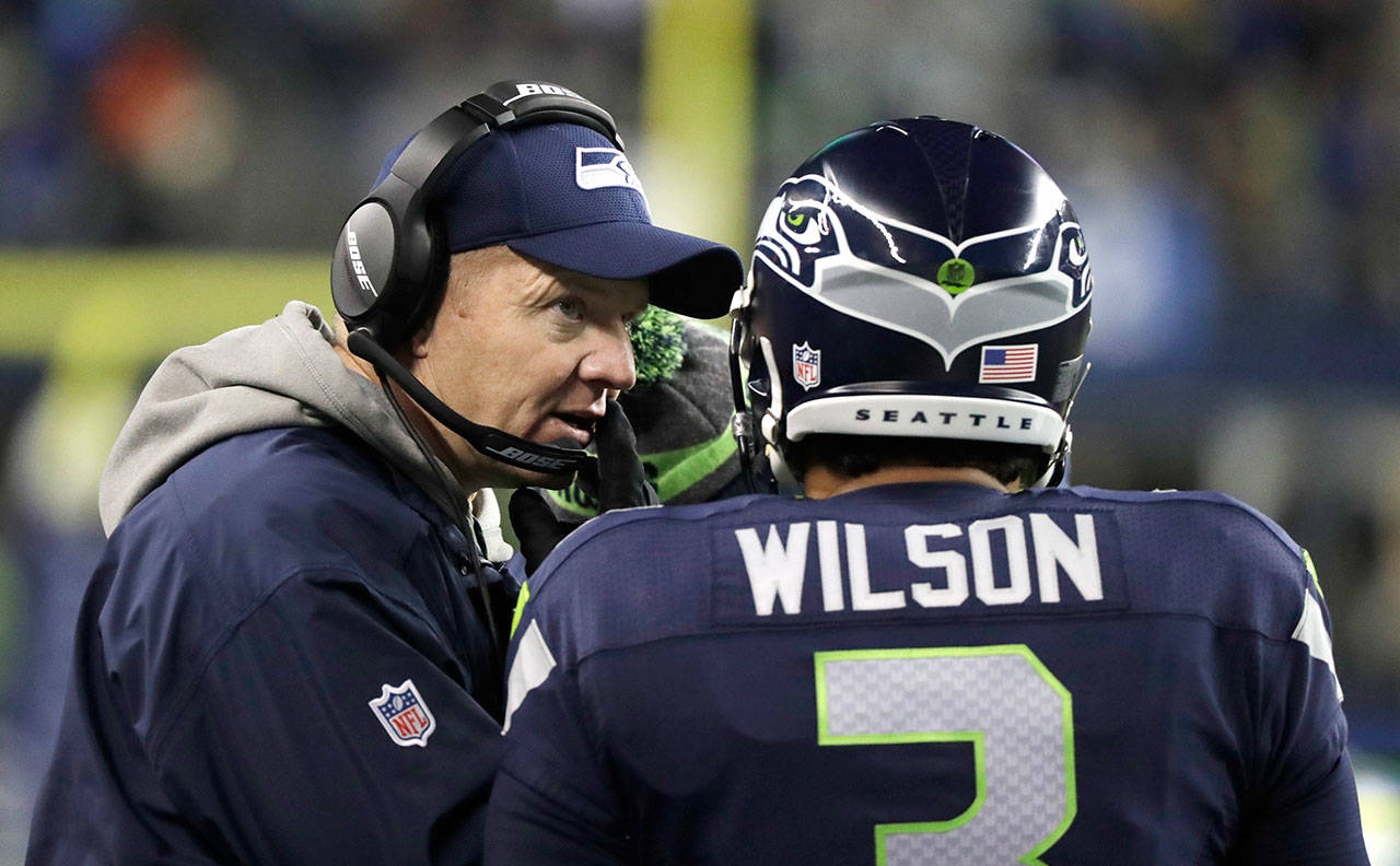 Seahawks quarterback Russell Wilson (3) confers with offensive coordinator Darrell Bevell in the second half of a playoff game against the Lions on Jan. 7, 2017, in Seattle. (AP Photo/Elaine Thompson)