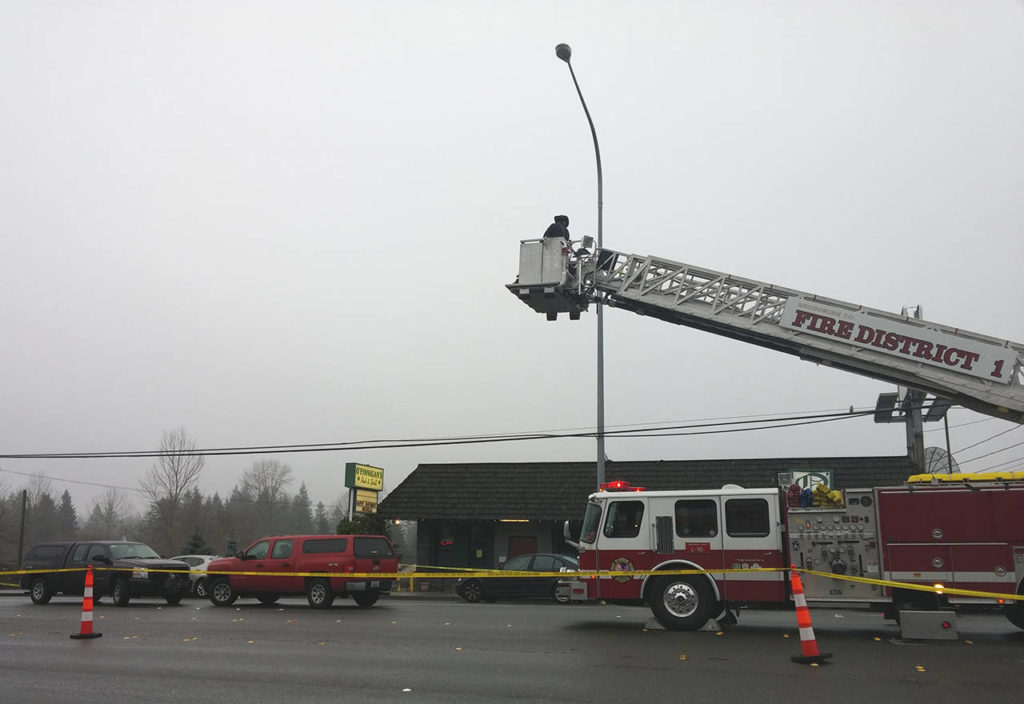 Investigators use a fire department ladder to get aerial views of the scene of a shooting on Saturday on Highway 99, between Everett and Lynnwood. (Rikki King / The Herald)
