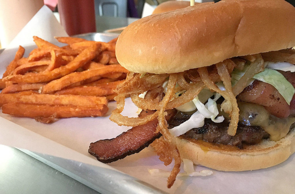 The Sweet Caroline at Blu Burgers & Brew in Mukilteo is a tangy, savory and sweet offering with a juicy beef patty, bacon slices, onion crisps, coleslaw and barbecue sauce. Opt for a side of sweet potato fries to complete the meal. (Ben Watanabe / The Herald)
