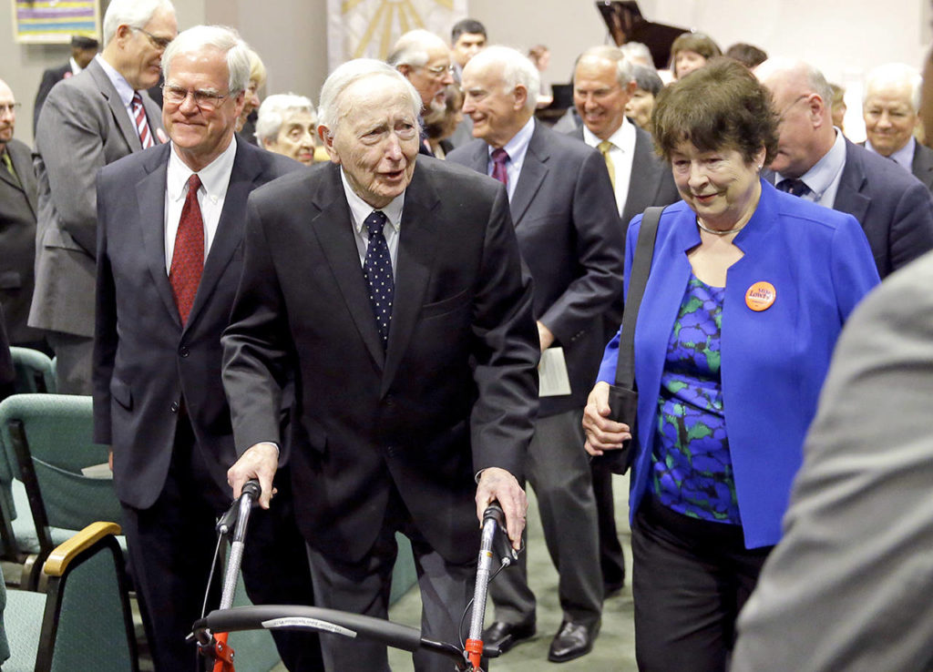 This May 30, 2017 photo shows former Washington Gov. John Spellman (using walker) and Sen. Maralyn Chase, D-Edmonds (in blue), leaving a memorial service in Renton. (AP Photo/Ted S. Warren,File)

