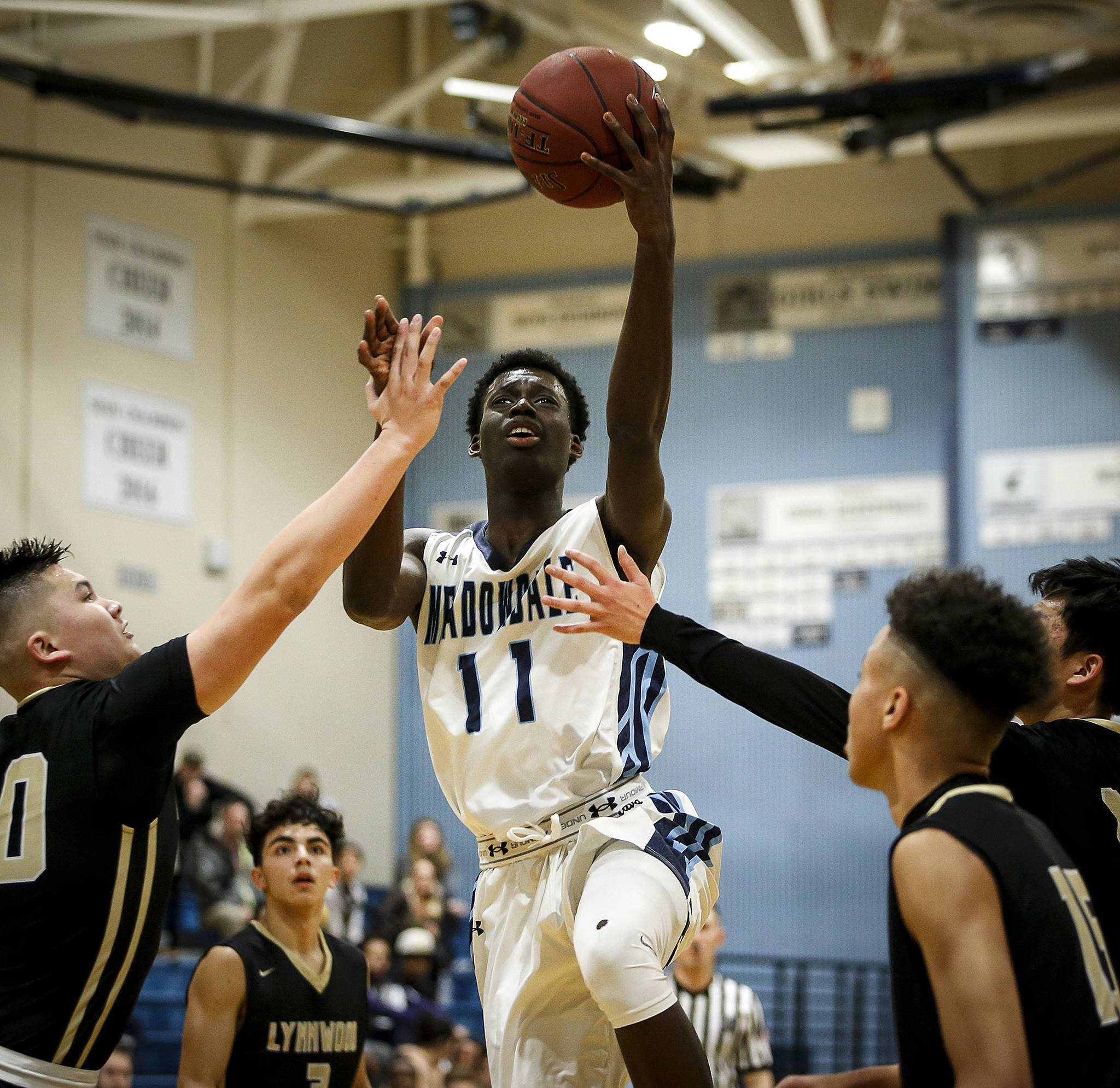 Meadowdale’s Mustapha Sonko (center) drives through a host of Lynnwood defenders for a layup during a game on Jan. 16, 2018, at Meadowdale High School in Lynnwood. (Ian Terry / The Herald)