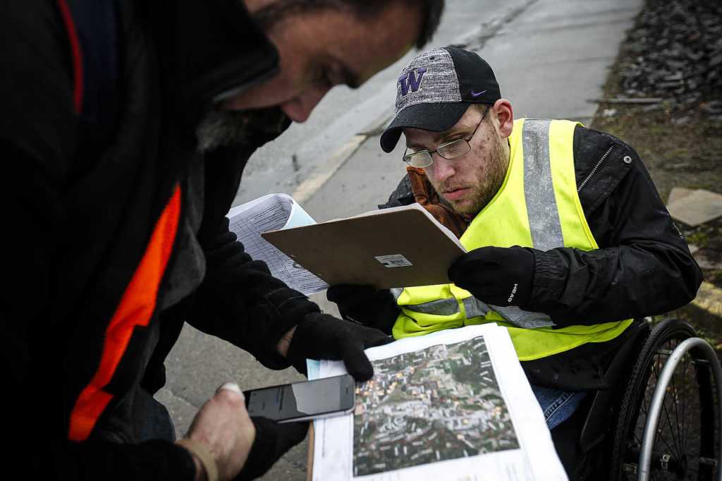 Tyson Kuntz (right), a volunteer with AmeriCorps, and Paul Olson, check maps while out in the Smokey Point area surveying the homeless population Tuesday. (Ian Terry / The Herald)
