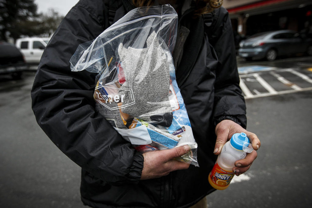 Scott Armstrong holds supplies including clean socks, toiletries and snacks given to him by volunteers Tuesday in Arlington. (Ian Terry / The Herald)

