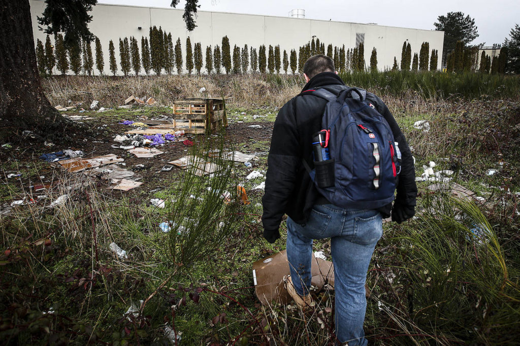 Volunteer Paul Olson, of Everett, walks through a former homeless encampment near Smokey Point Boulevard on Tuesday. (Ian Terry / The Herald)
