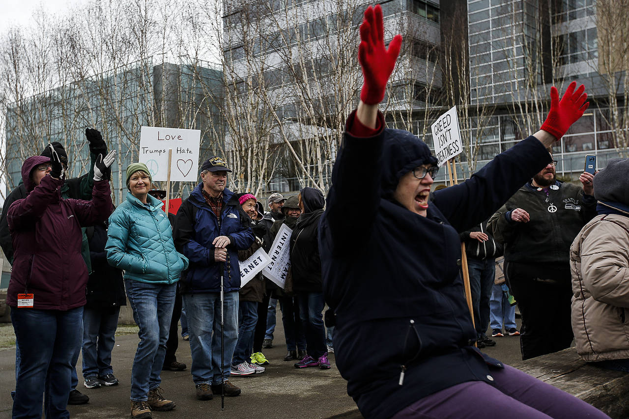People cheer as they listen to speakers gathered outside the Snohomish County courthouse in Everett during a rally to protest the 1-year anniversary of the inauguration of President Donald Trump on Saturday. (Ian Terry / The Herald)