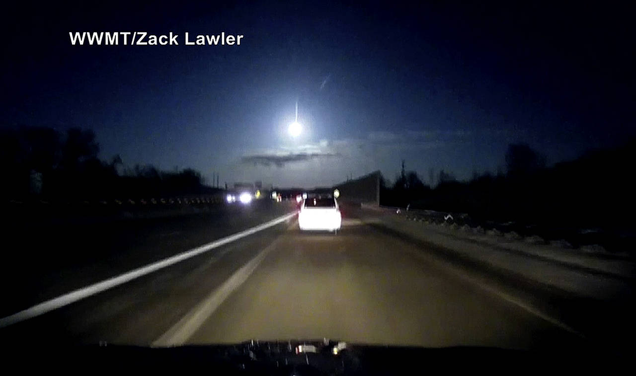 In this late Tuesday image made from dashcam video, a brightly lit object falls from the sky above a highway in the southern Michigan skyline. (Zack Lawler/WWMT via AP)